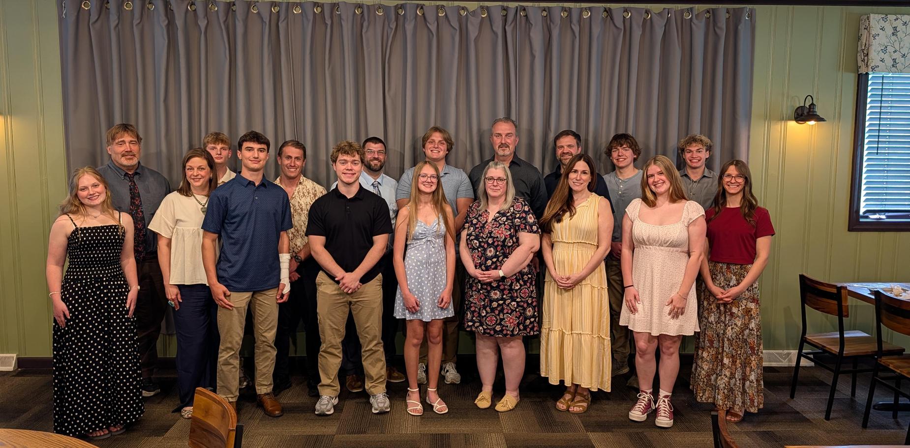 Formal group portrait of students and adults posing together in a restaurant.