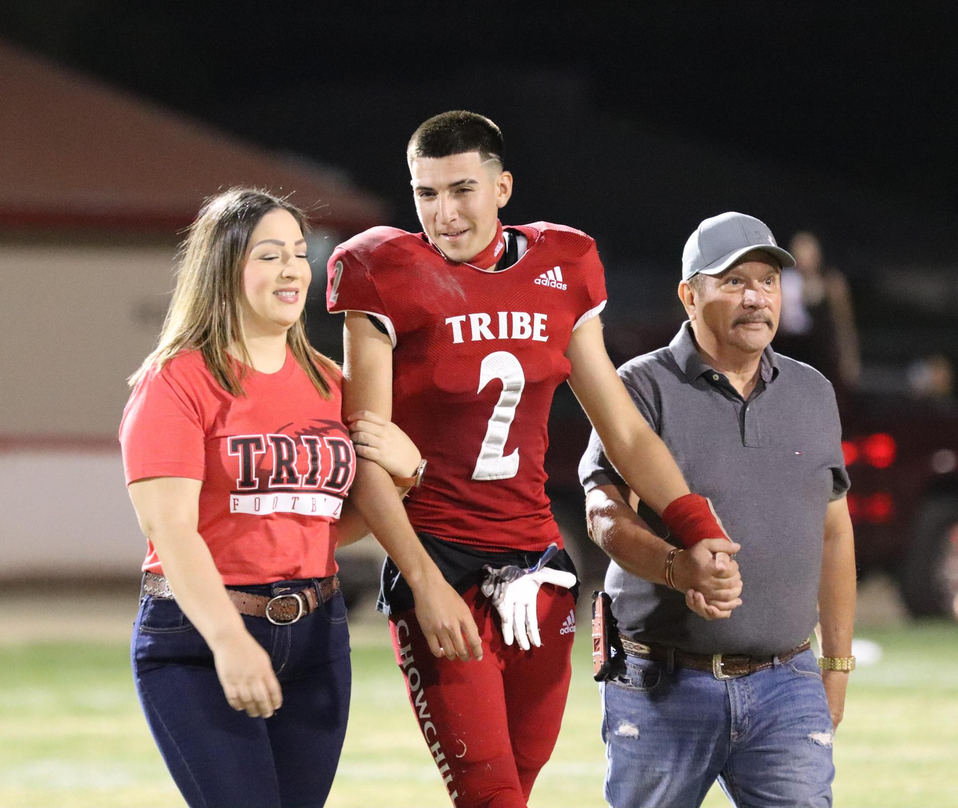 homecoming king and queen candidates walking across the field with their escorts