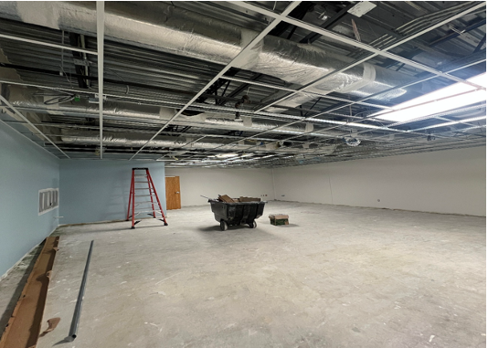 Empty interior room under construction with a ladder and debris on the floor.