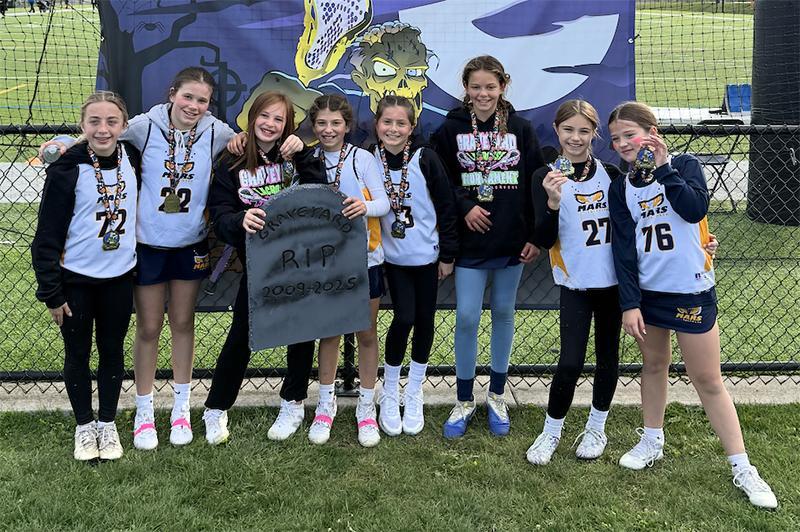 A group of girls wearing white lacrosse jerseys