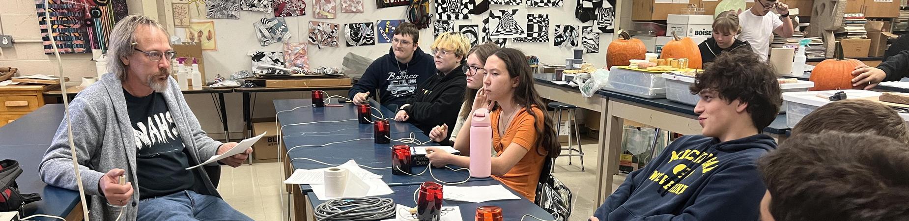 Teacher and students at desk.