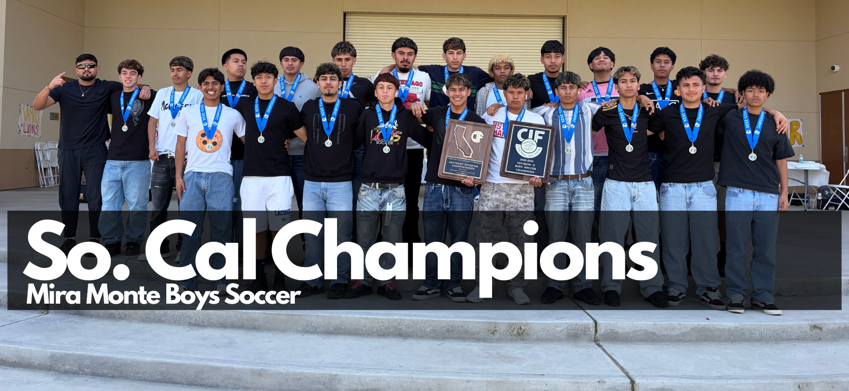 Group of young male soccer players celebrating a championship with medals and plaques.