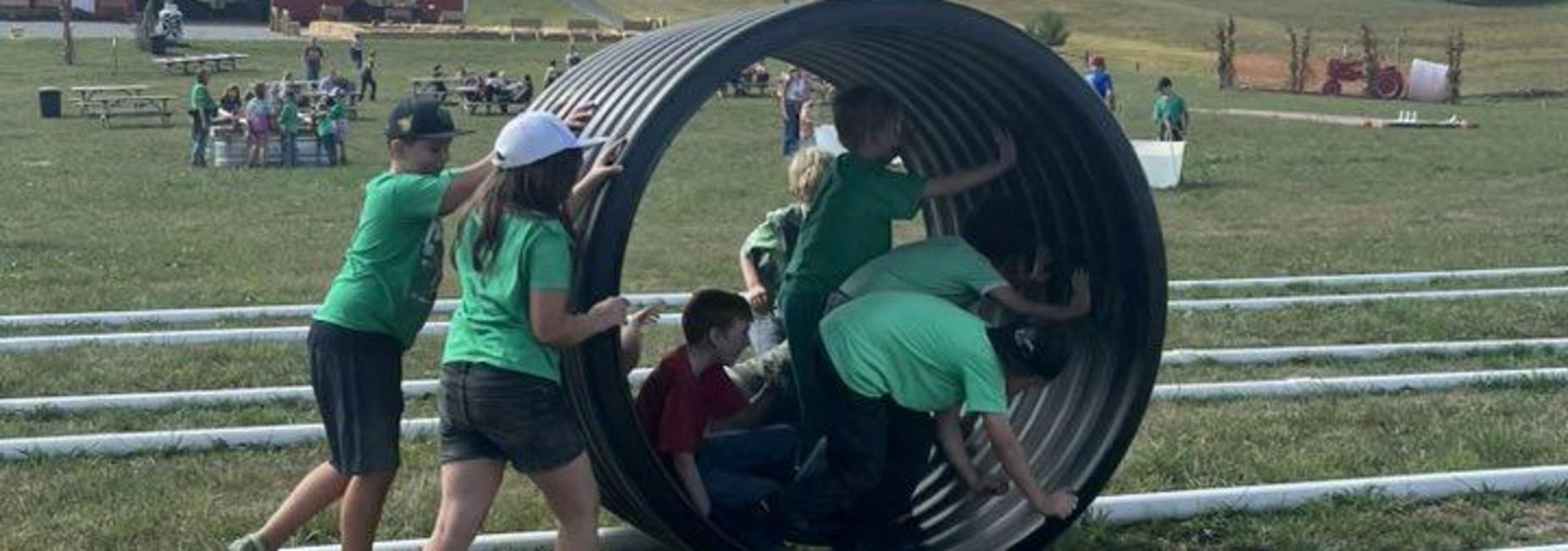 students roll inside large tube while on field trip to Richdale Farms