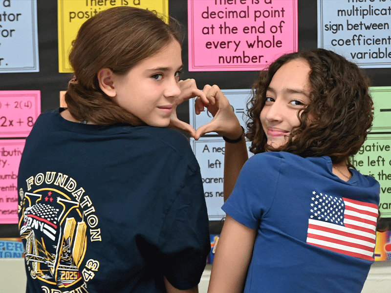 Two students with their backs turned making a heart with their hands