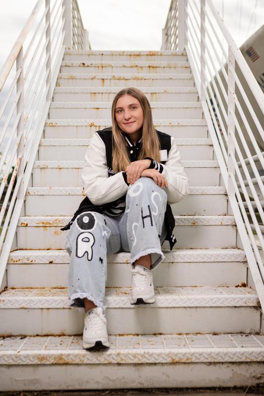 Woods sitting on stairs wearing letterman's jacket 2026