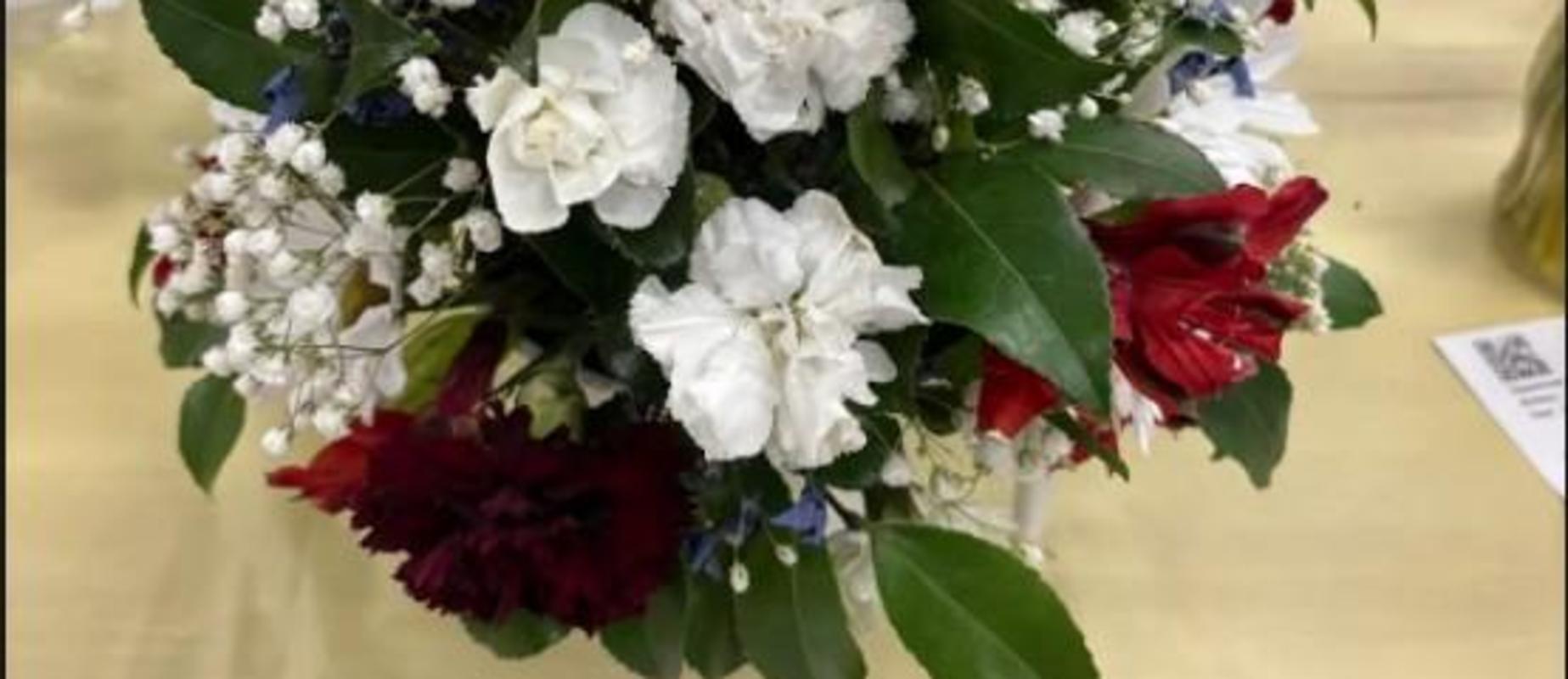 A vibrant floral bouquet with white, red, and blue flowers arranged elegantly.
