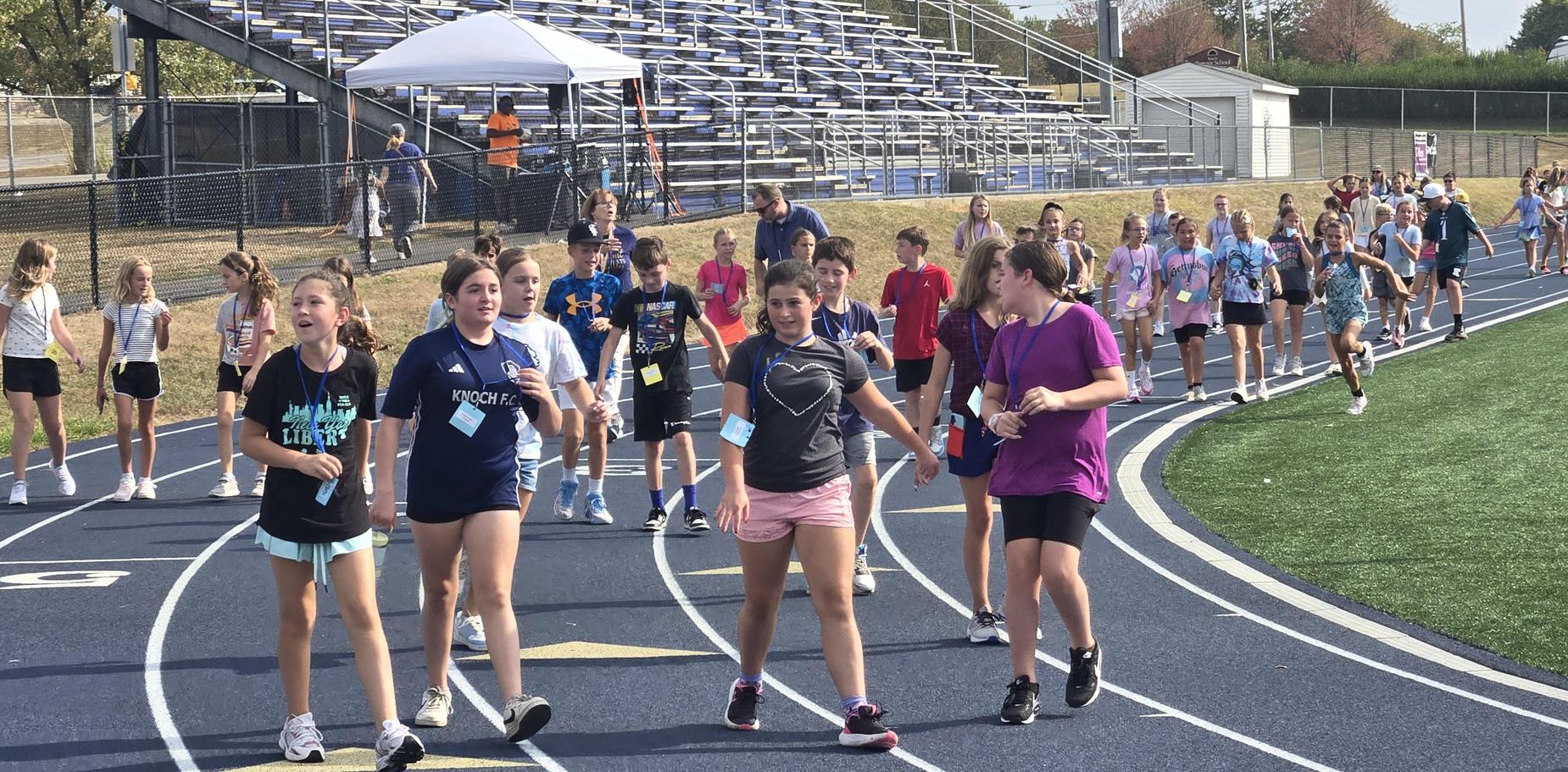 Groups of students walking on a running track, participating in a school activity.