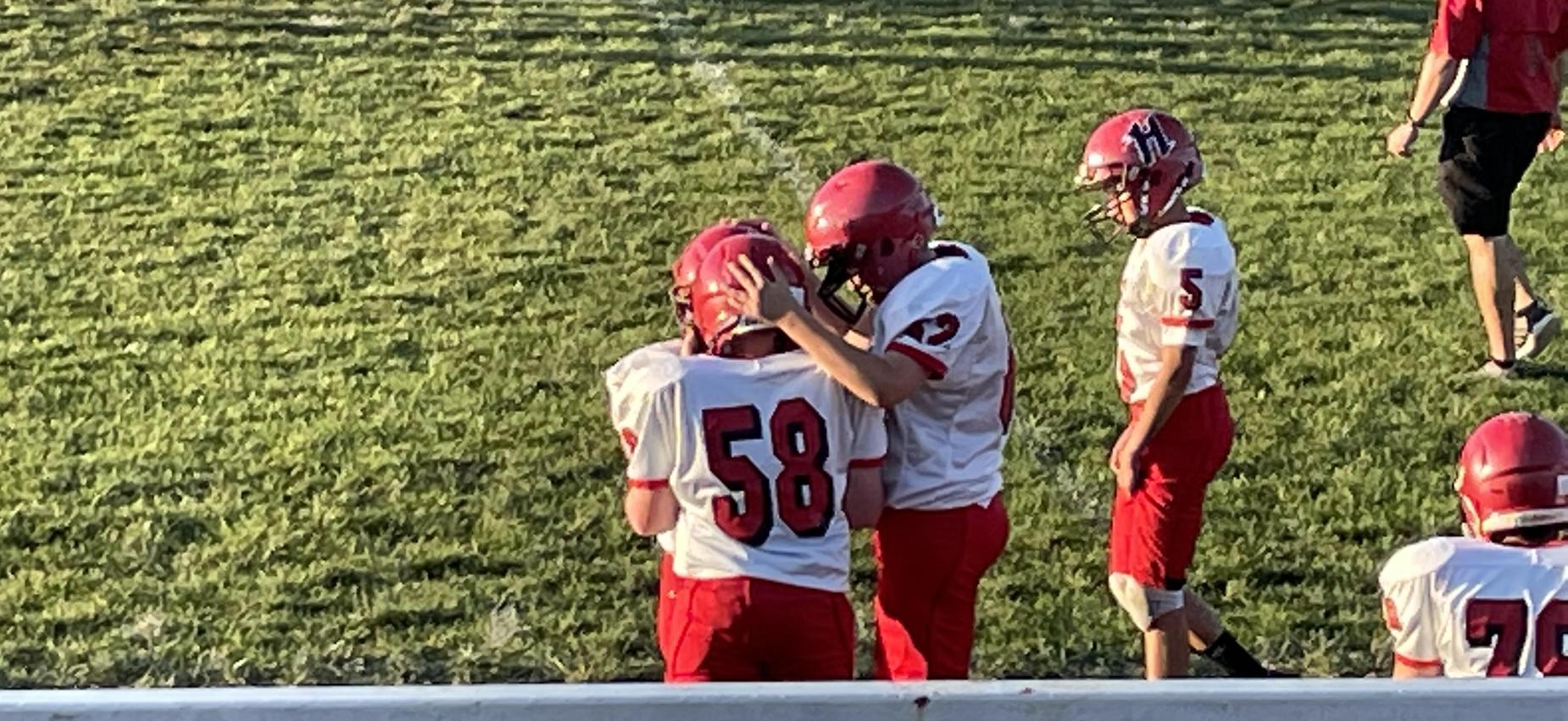 Football players stand on a field.