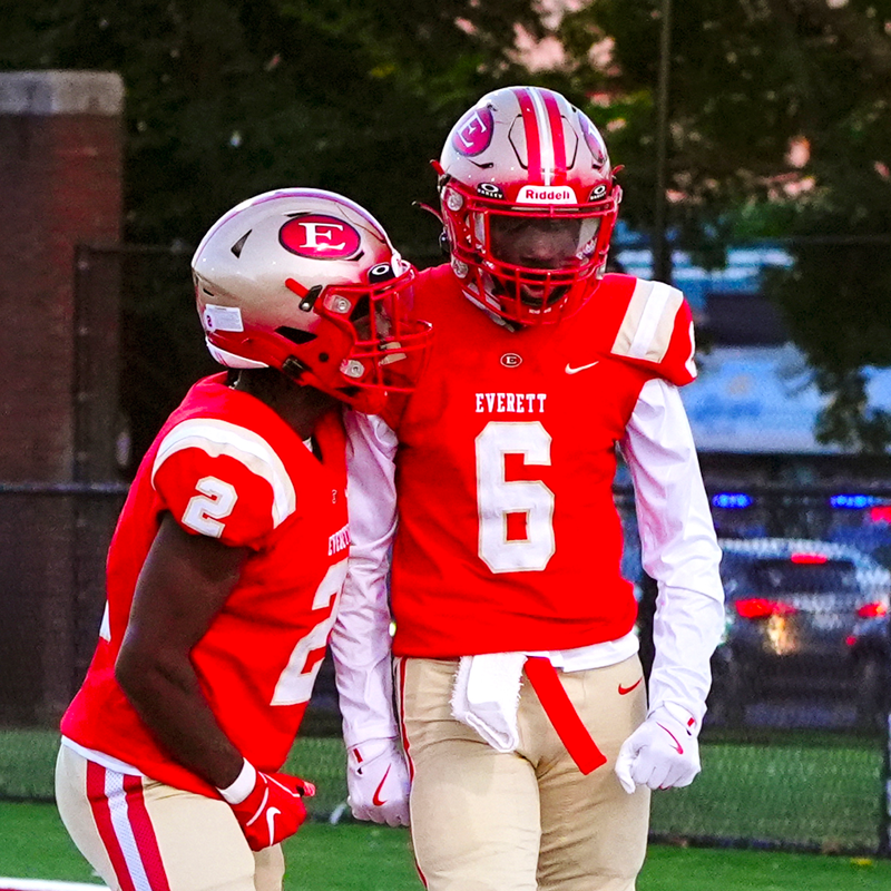 Two football players on the field, standing side by side in between plays