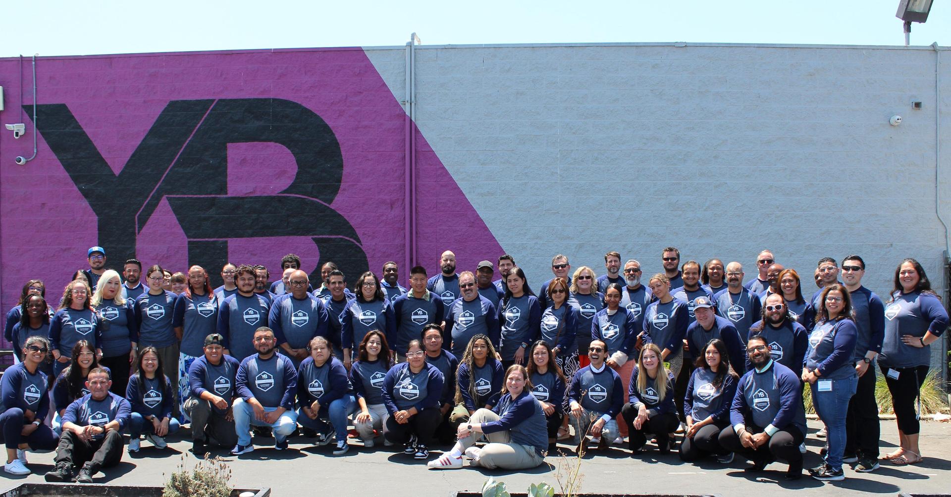 School staff pose outside the YB sign at Compton YouthBuild