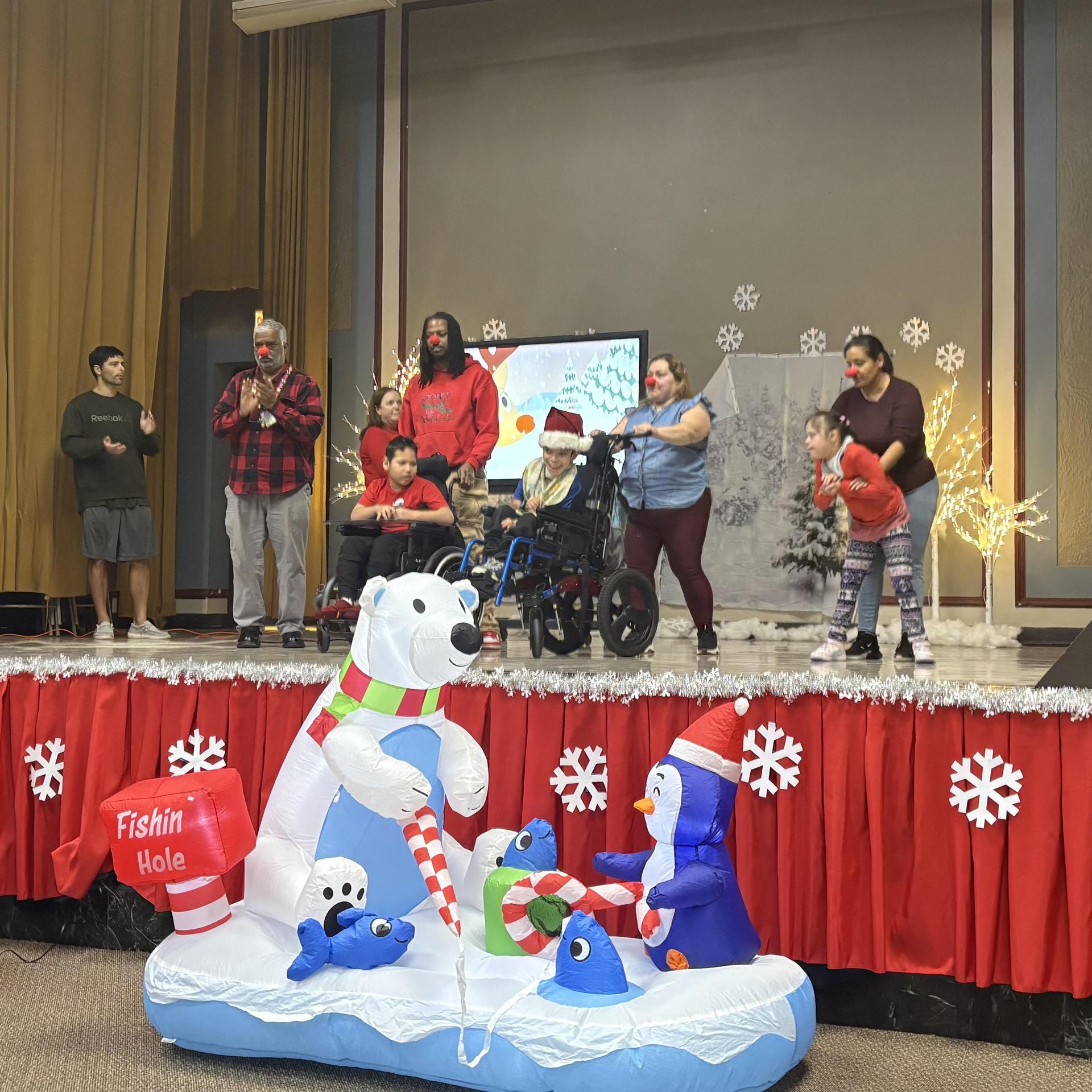 Participants performing on stage with a festive backdrop and inflatable decorations.
