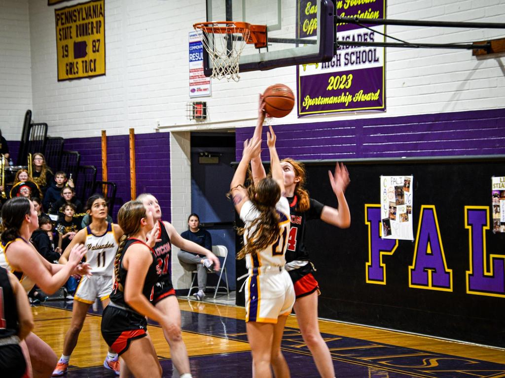 Basketball players on the court making a shot.