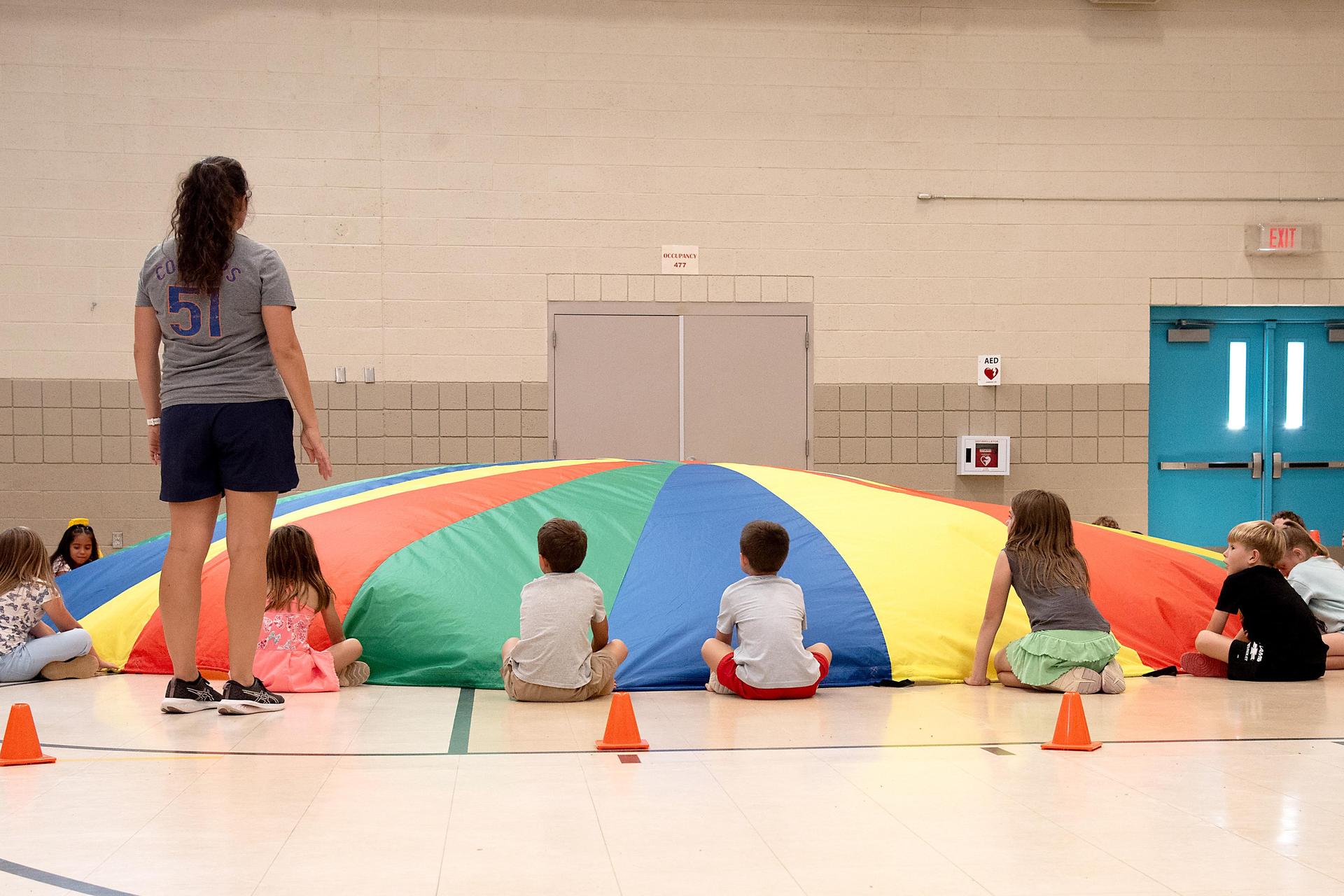 children playing with large parachute in P.E. class