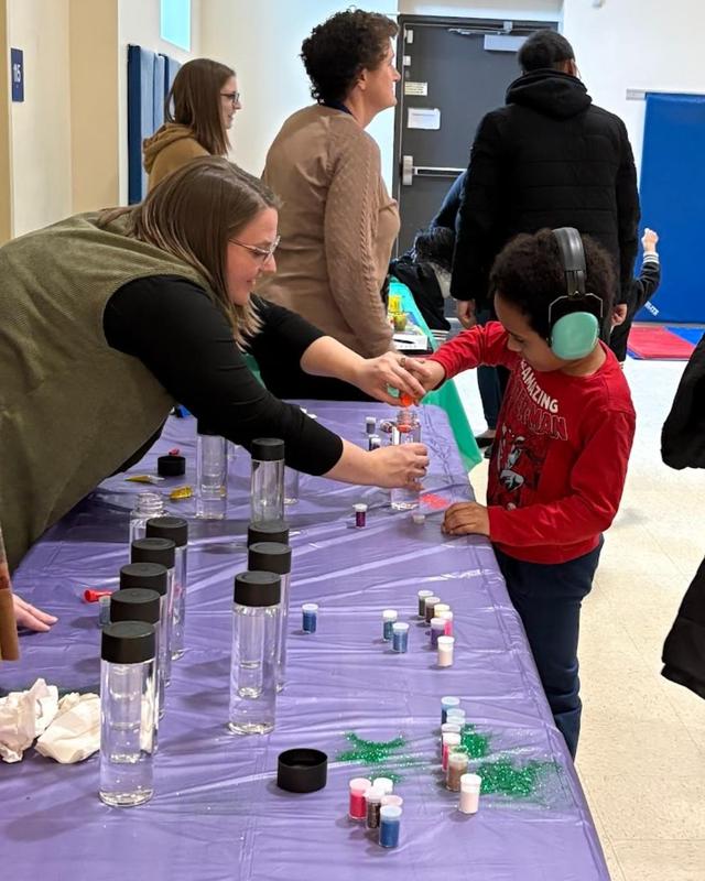 a teacher and a student placing beads into a glass beaker
