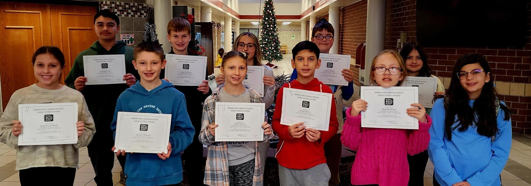 Group of students proudly holding certificates in a festive hall.