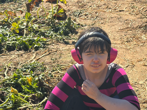 student smiling for camera, sitting in pumpkin patch