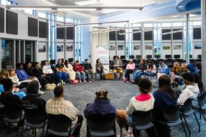 Students and Joy sit in a circle to discuss writing