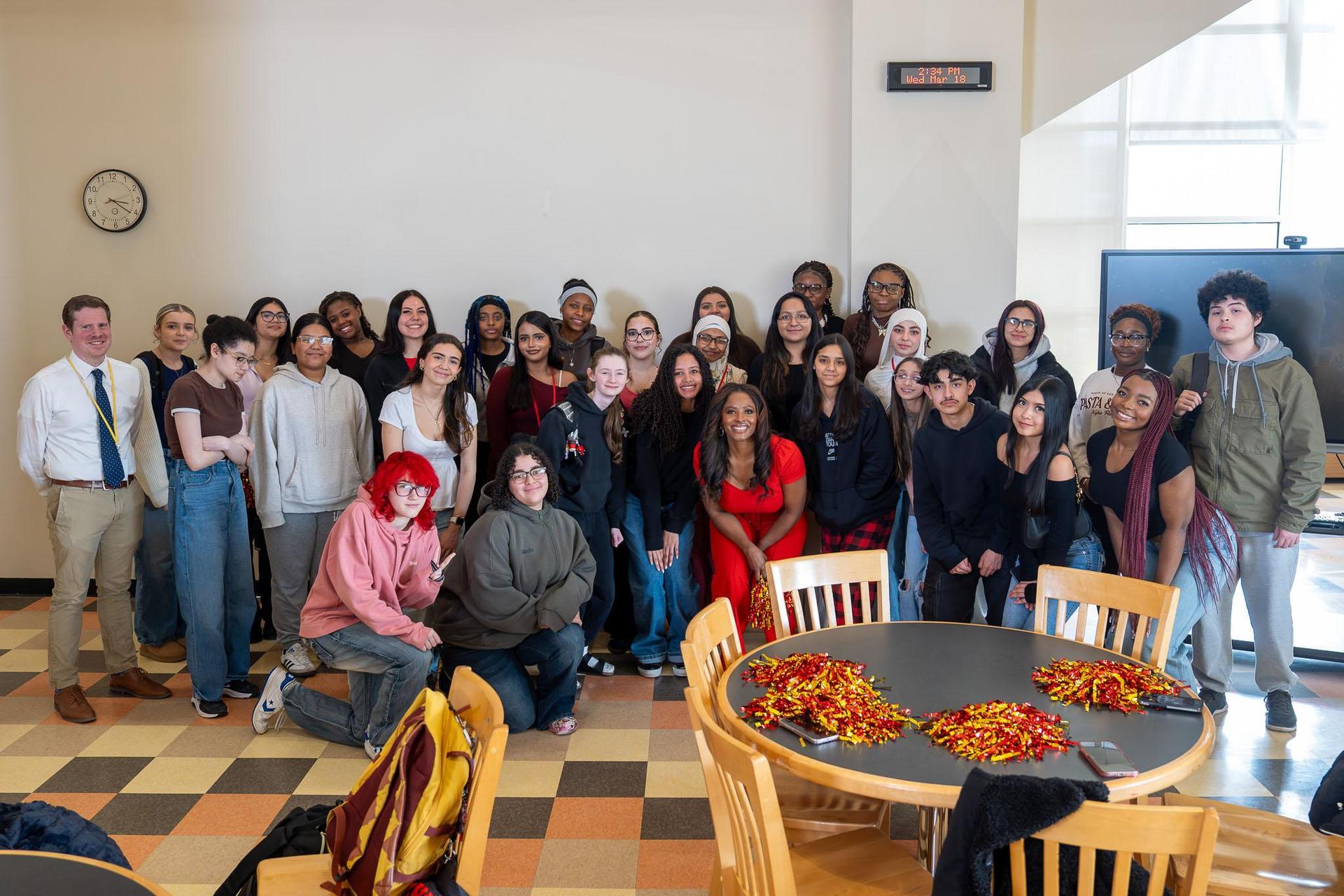 A large group of students and adults posing together in a classroom setting.