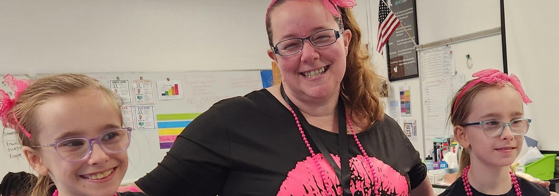 Two girls in black tops and pink tutus posing with an adult in a matching outfit.