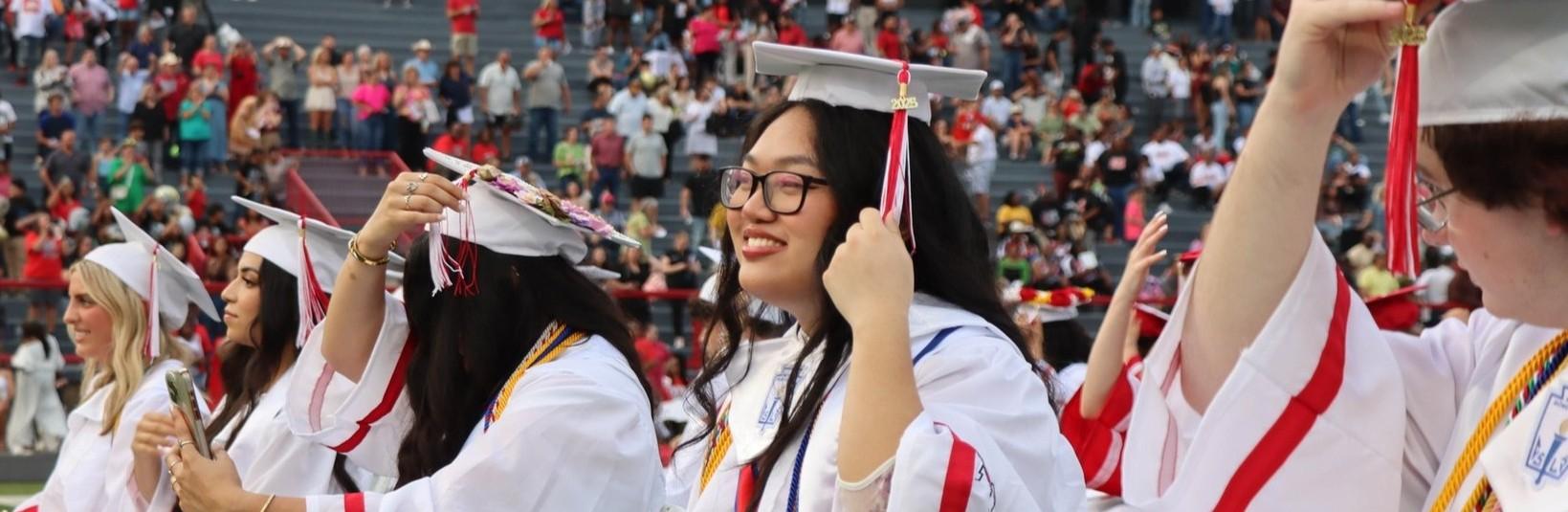 Graduates in caps and gowns celebrating during a graduation ceremony.