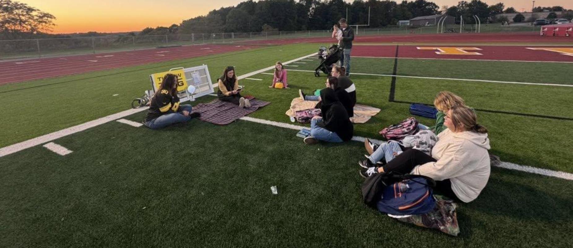 Families reading with children duing Title I Fall Literacy Reading Under the Lights event at Trojan Stadium