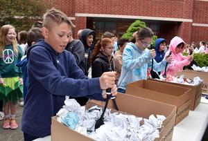 Children participate in an outdoor activity involving boxes and paper shreds.