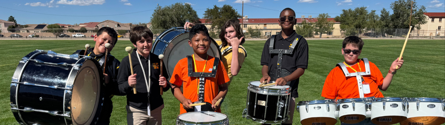Students posing with drums in a sunny field