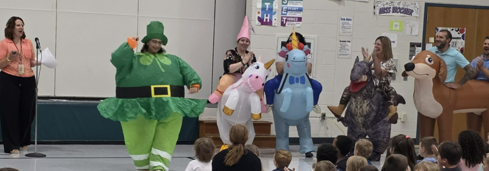 A group of people in colorful costumes entertaining a crowd of children.