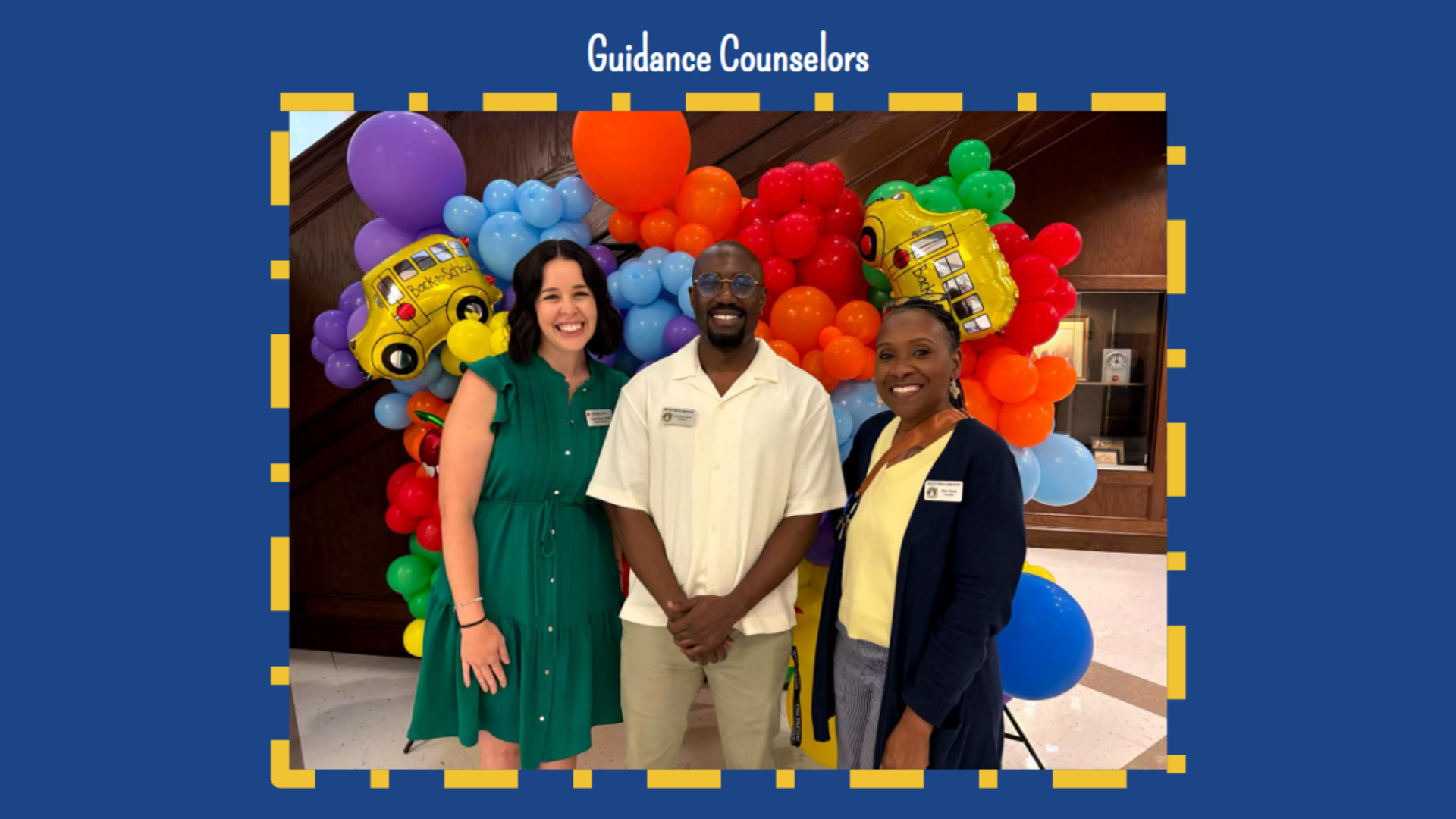 Three guidance counselors pose in front of colorful balloons.