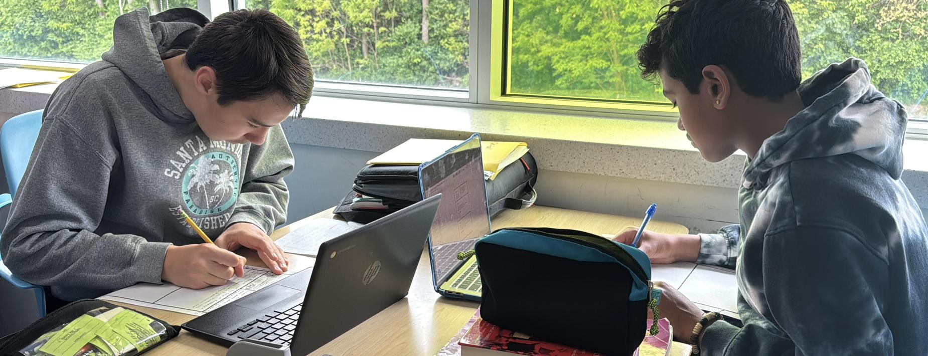 two students sitting at a table doing homework