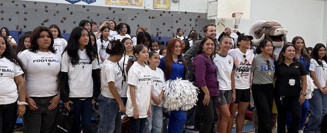 A large group of students, cheerleaders, and staff dressed in matching shirts at a gym event.