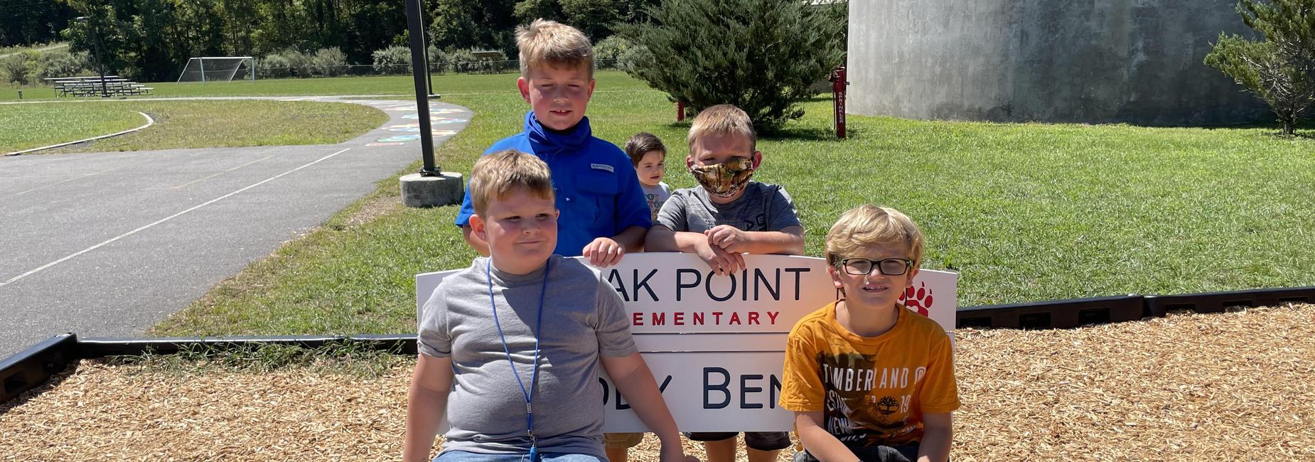 Photo of Oak Point students sitting on the new Buddy Bench on the playground