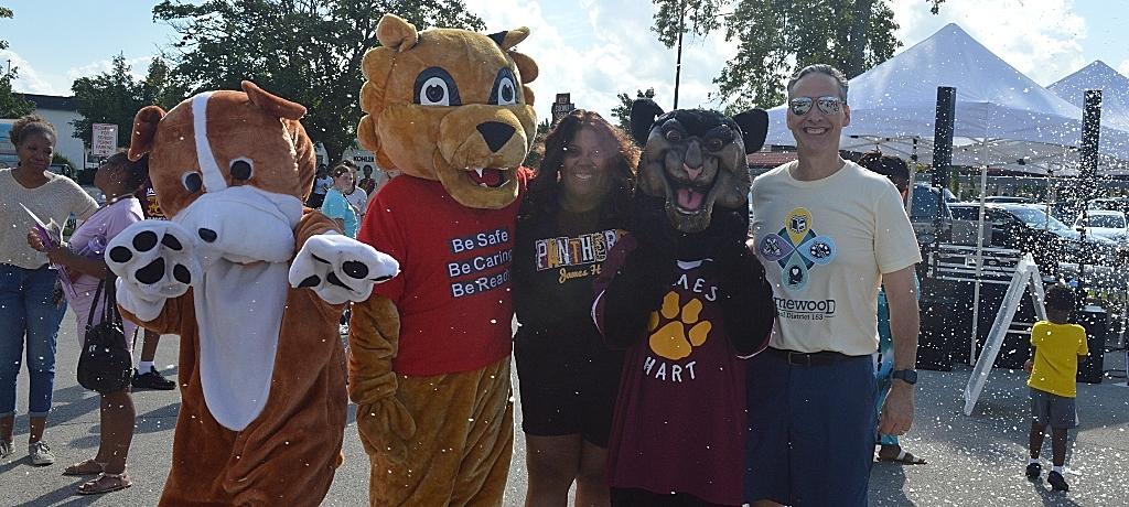 Superintendent and Principal pose for photo with 3 school mascots.