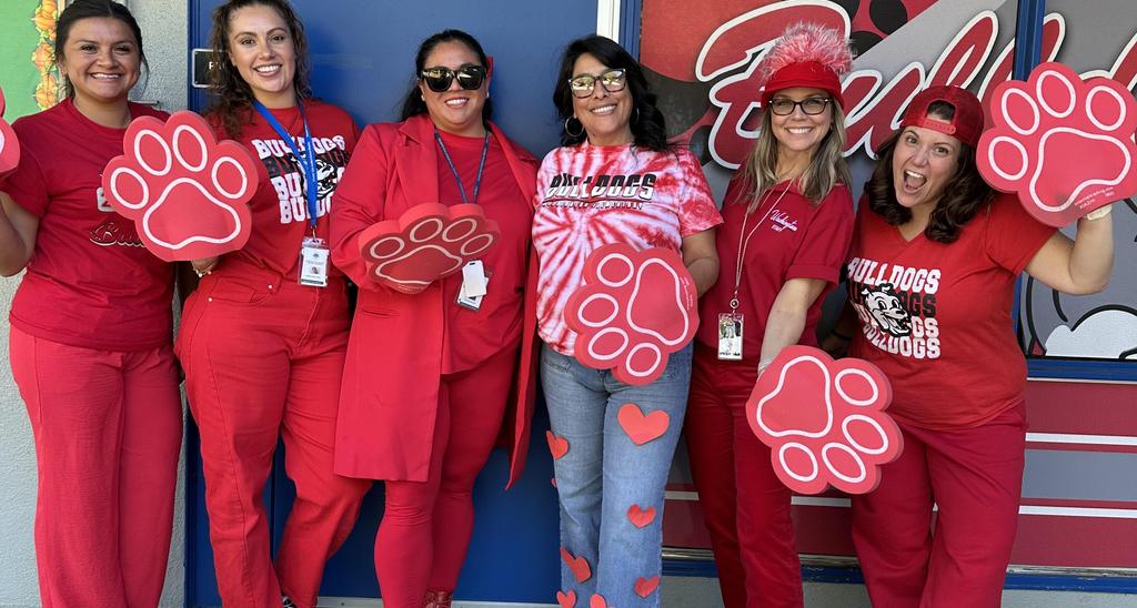 Group of six women dressed in red with paw-shaped signs.