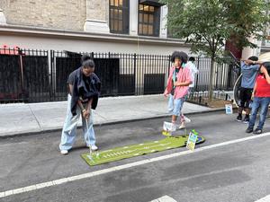 Two children playing a floor game outdoors on a city street.