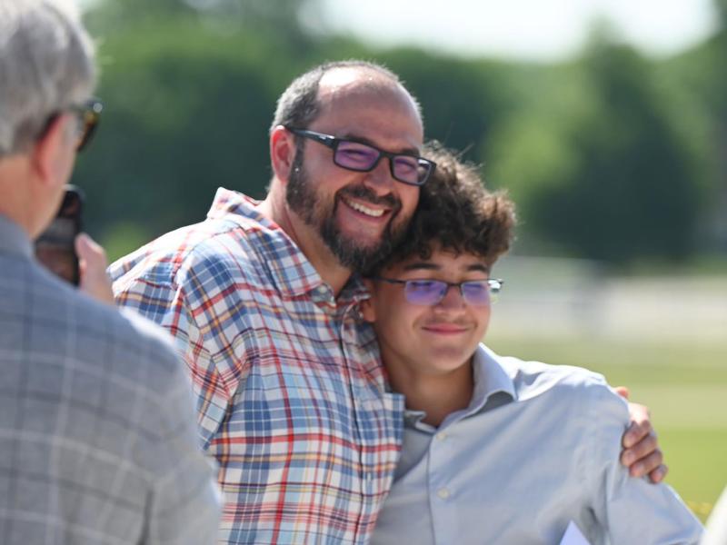 Man and boy pose for a cheerful photo during an outdoor event.
