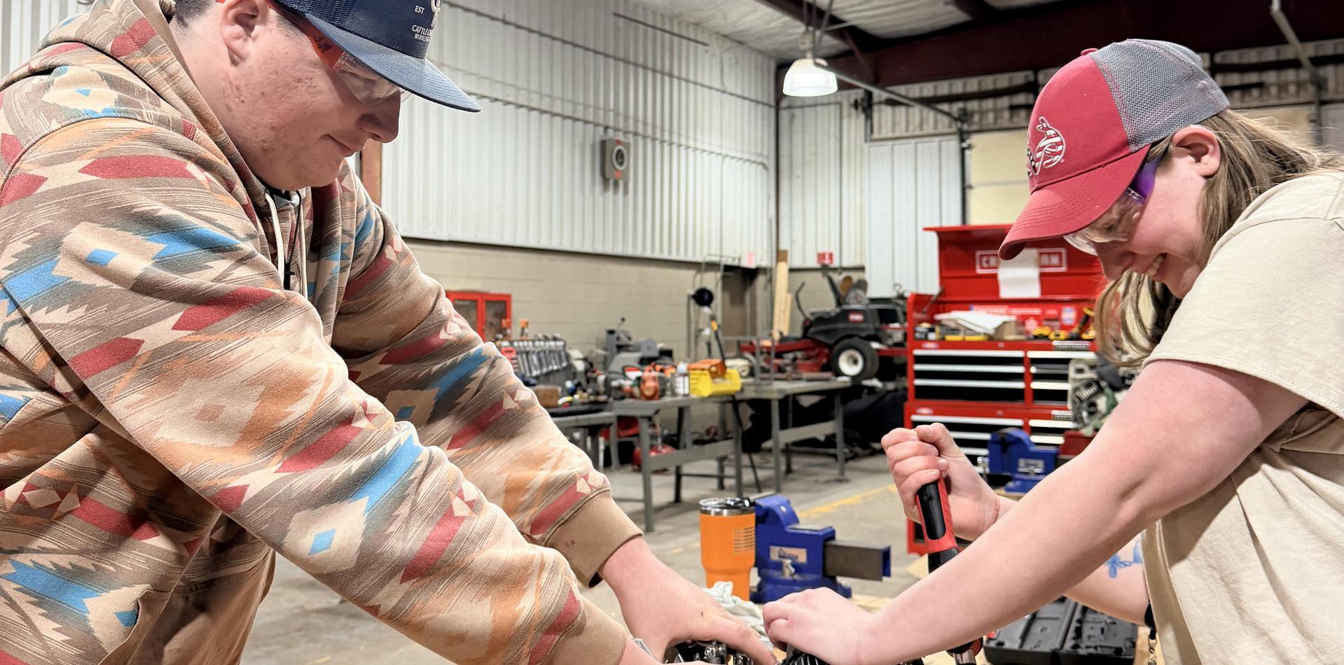 Two individuals working together in a workshop, engaged in a task.