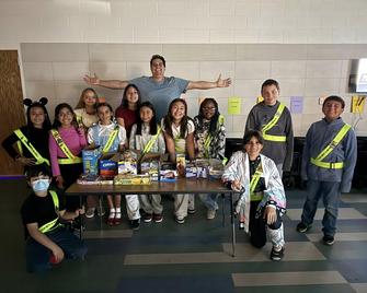 Coach in gray shirt standing behind group of safety patrols wearing neon yellow belts