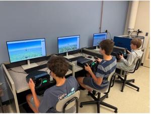 Students sit at computers, interacting with flight simulators.