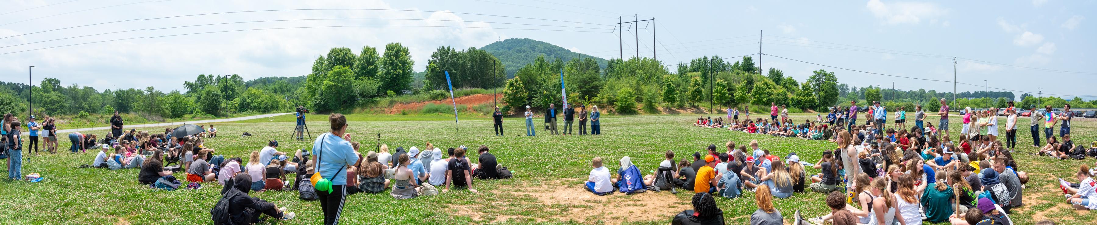 Panoramic photo of a groundbreaking ceremony in a field with students and staff