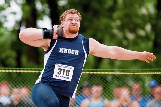 high school senior boy has shot put on shoulder about to throw