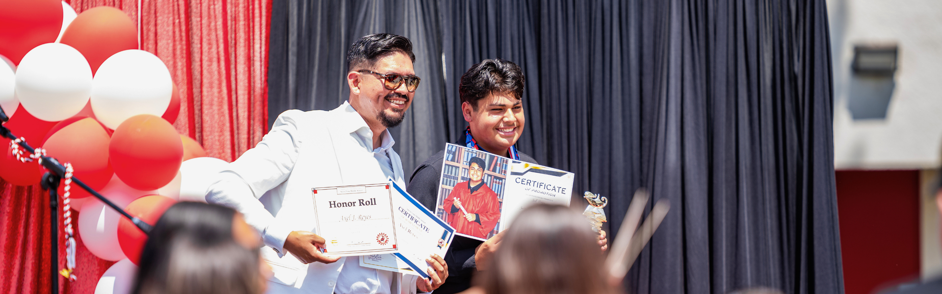 A student receives awards with a Principal at a celebration.