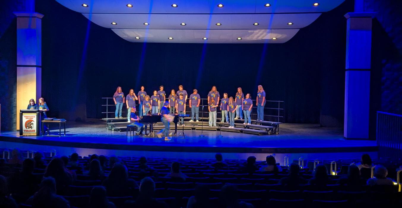 A choir performing on stage with audience members seated below.