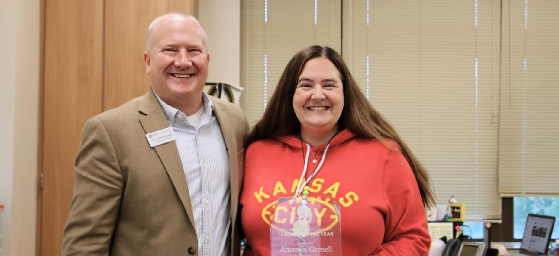 Two smiling educators posing with an award plaque.