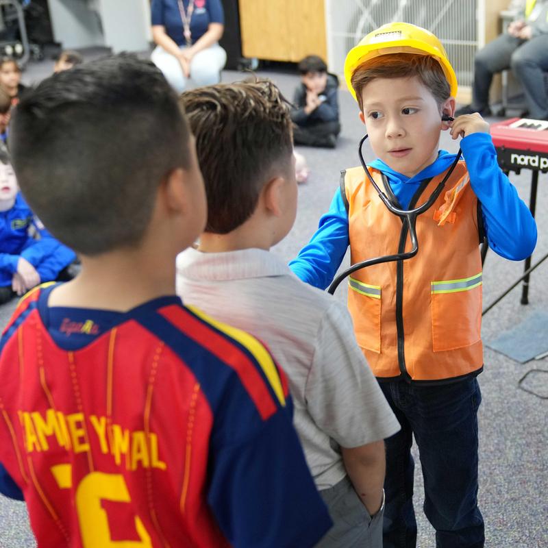 student dressed as a builder listens to heartbeat of classmate