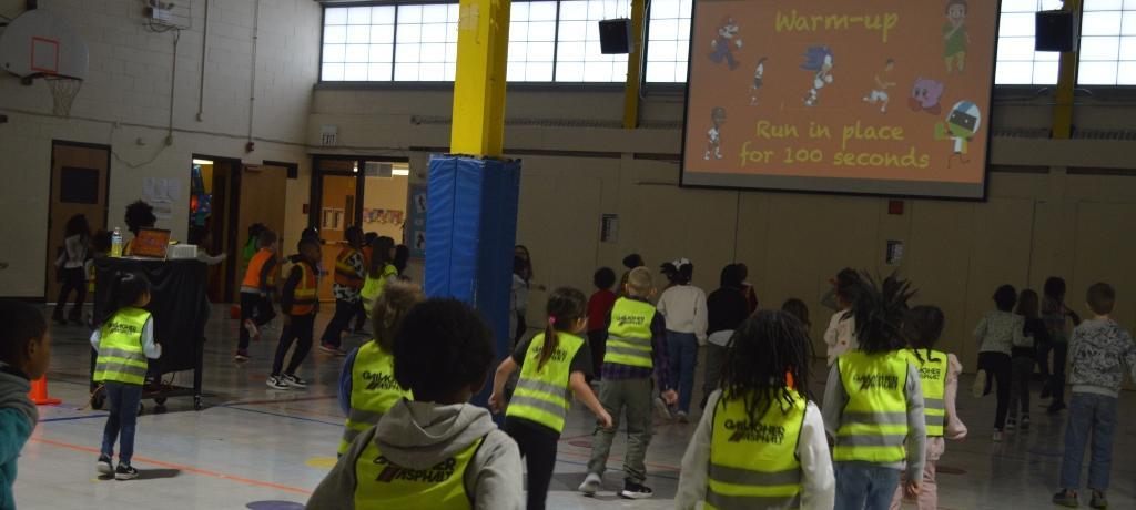 students in safety vests run in place
