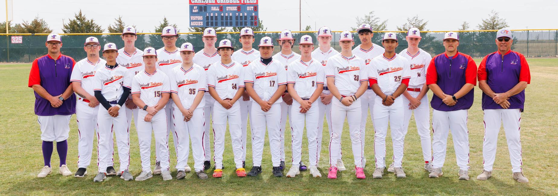 Team of young baseball players in white uniforms standing on a field.