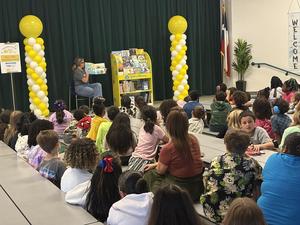 A guest reader shares a book with students