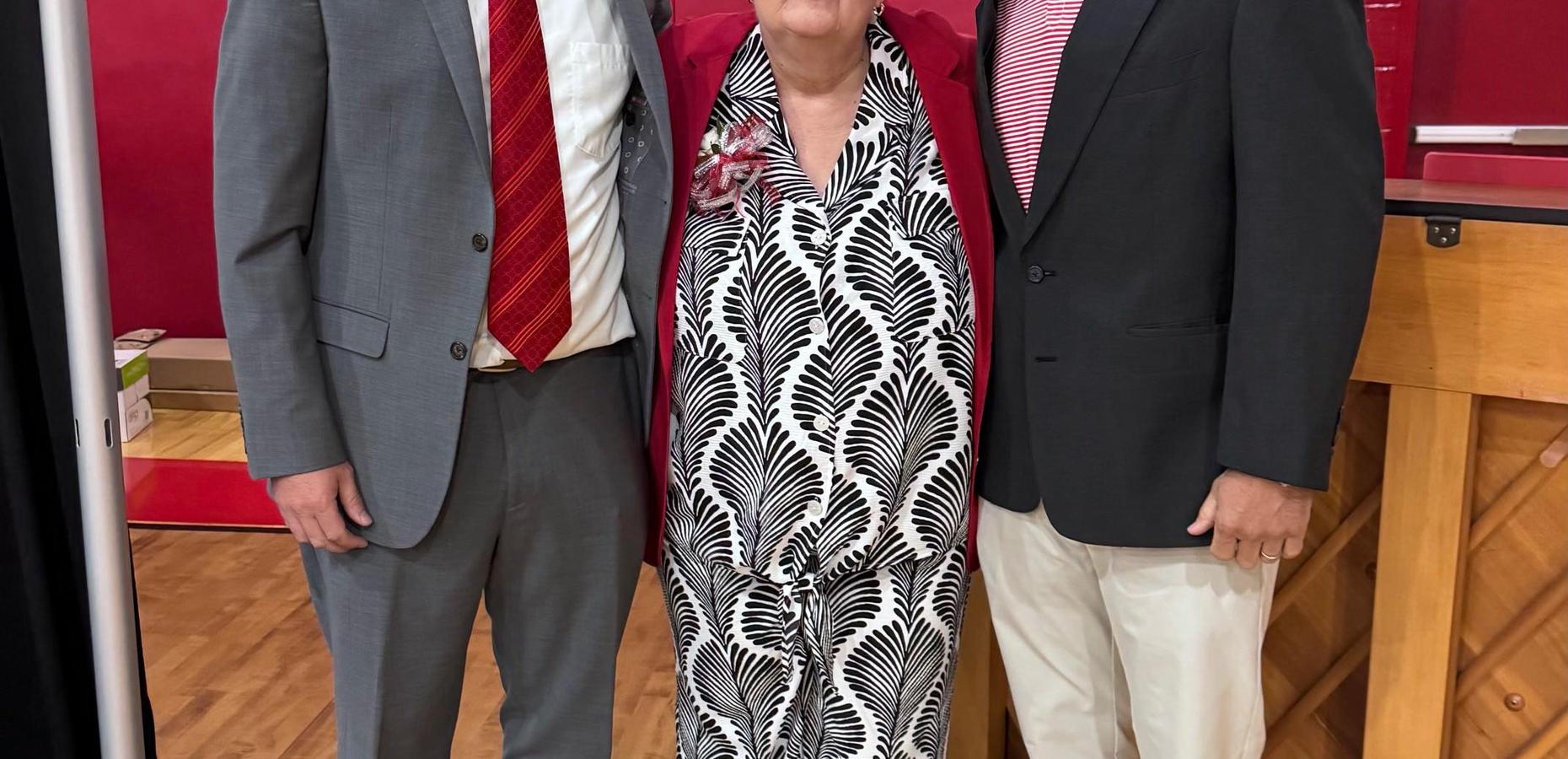Three adults posing together at a formal gathering.