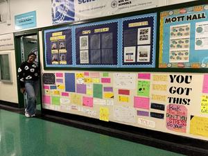Ms.Diallo standing in front of message wall